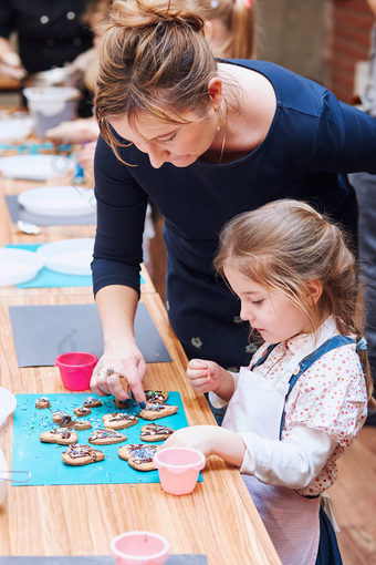 小女孩与她的妈妈rsquo帮助装修烤饼干与色彩斑斓的撒上和糖衣糖孩子采取部分烘焙车间烘焙类为孩子们有抱负的小厨师学习烹饪结合和激动人心的准备成分真正的人真实的的情况下