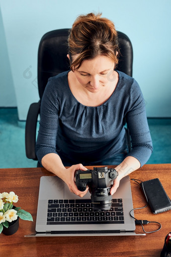 女摄影师<strong>工作照片</strong>移动PC和相机女人编辑修版浏览照片工作自由职业者坐着桌子上