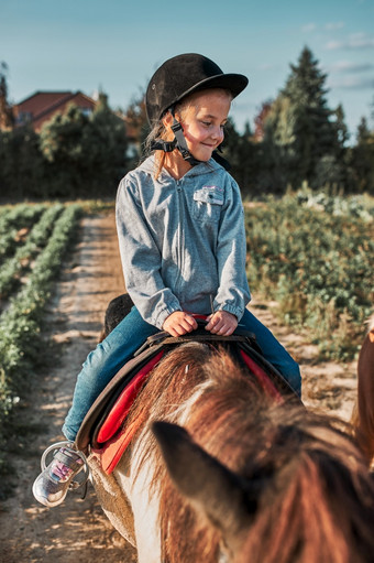 小微笑女孩<strong>学习</strong>马背上的骑年老马术头盔有有趣的骑马小微笑女孩<strong>学习</strong>马背上的骑