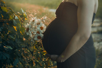 怀孕了女人拥抱她的肚子站在户外包围自然怀<strong>孕期</strong>望母亲概念