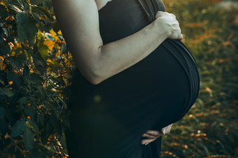 怀孕了女人拥抱她的肚子站在户外包围自然怀<strong>孕期</strong>望母亲概念