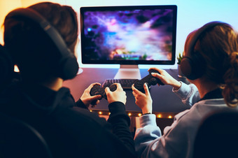 朋友玩视频游戏首页游戏玩家持有游戏手柄坐着前面屏幕飘带女孩和男孩玩在线黑暗房间基斯霓虹灯灯竞争和有有趣的