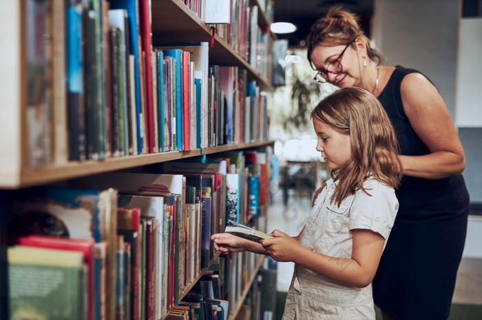 老师帮助选择书她的女学生学校图书馆聪明的女孩选择文学为阅读书货架上书店学习从书学校教育好处日常阅读孩子好奇心