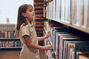 女学生选择书学校图书馆聪明的女孩选择书书货架上书店学习从书学校教育好处日常阅读孩子好奇心回来学校