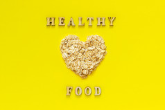 文本健康的食物和燕麦片燕麦片形状心黄色的背景海尔西有机饮食概念前视图文本健康的食物和燕麦片燕麦片的形状心黄色的背景