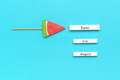 木日历夏天个月6月7月8月和西瓜棒棒糖坚持蓝色的背景概念假期假期你好6月有创意的前视图模板木日历夏天个月6月7月8月和西瓜棒棒糖坚持蓝色的背景概念假期假期你好6月有创意的前视图模板