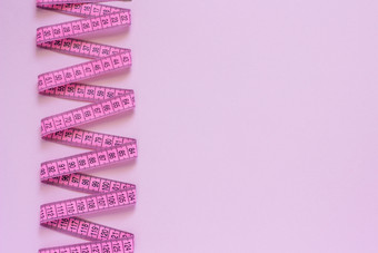 粉红色的磁带测量成螺旋形地铺设粉红色的背景复制空间前视图粉红色的磁带测量成螺旋形地铺设粉红色的背景