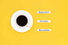 木日历秋天个月9月10月11月和杯黑色的咖啡目的是11月黄色的背景概念前视图平躺复制空间杯咖啡和日历11月10月9月黄色的背景