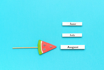 木日历夏天个月8月6月7月和西瓜棒棒糖坚持蓝色的背景概念假期假期你好8月有创意的前视图模板木日历夏天个月8月6月7月和西瓜棒棒糖坚持蓝色的背景概念假期假期你好8月有创意的前视图模板