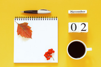 秋天作文木日历11月杯咖啡空开放记事本与笔和黄色的橡木叶黄色的背景前视图平躺模型概念你好11月日历11月杯咖啡记事本与笔和黄色的叶黄色的背景
