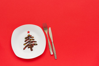 节日甜点甜蜜的圣诞节树使巧克力与五彩缤纷的洒白色板和餐具红色的背景概念圣诞节新一年rsquo治疗的节日表格前视图复制空间甜蜜的巧克力圣诞节树板和餐具
