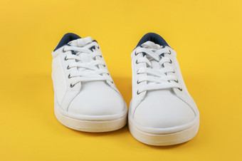 白色体育鞋子运动鞋与鞋带黄色的背景体育运动生活方式概念前视图平躺复制空间白色体育鞋子运动鞋与鞋带黄色的背景体育运动生活方式概念前视图平躺复制空间