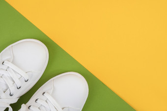 白色体育鞋子运动鞋与鞋带绿色和黄色的背景体育运动生活方式概念前视图平躺白色体育鞋子运动鞋与鞋带绿色和黄色的背景体育运动生活方式概念前视图平躺
