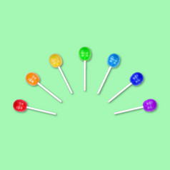 集色彩斑斓的棒棒糖分组一半圆孤立的绿色背景糖果坚持食物背景平躺