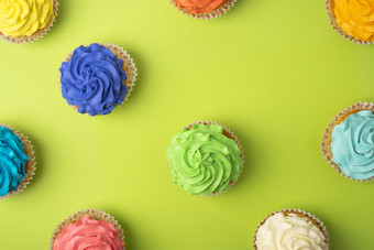 聚会，派对背景与不同的纸杯蛋糕明亮的绿色背景模式与纸杯蛋糕与色彩斑斓的糖衣聚会，派对背景与纸杯蛋糕明亮的绿色背景