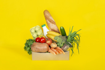 食物交付购物捐赠概念食物交付在冠状病毒检疫纸盒子与不同的食物成分这样的水果蔬菜牛奶鸡蛋孤立的黄色的背景食物交付购物捐赠概念