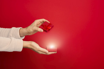 女手持有开放红色的小珠宝盒子与内心的发光红色的背景礼物现在网购概念横幅与复制空间女手持有开放红色的小珠宝盒子红色的背景