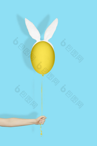有<strong>创意</strong>的复活节最小的概念手持有黄色的蛋兔子耳朵就像气球字符串光<strong>蓝色</strong>的背景有<strong>创意</strong>的复活节最小的概念手持有黄色的蛋兔子耳朵就像气球字符串光<strong>蓝色</strong>的背景