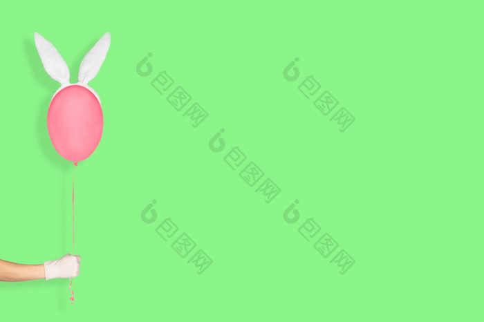 有创意的复活节最小的概念手白色手套持有粉红色的气球兔子耳朵孤立的柔和的绿色背景复活节横幅与复制空间有创意的复活节最小的概念手白色手套持有粉红色的气球兔子耳朵孤立的柔和的绿色背景复活节横幅与复制空间