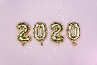 快乐新一年庆祝活动黄金箔气球数字和金星星柔和的粉红色的背景假期聚会，派对装饰快乐新一年庆祝活动黄金箔气球数字和金星星柔和的粉红色的背景平躺