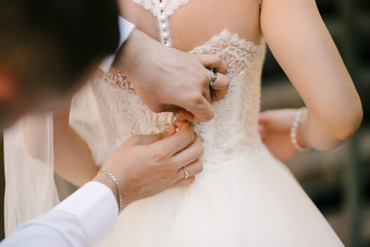 白色婚礼衣服针织的新娘新娘被帮助穿的婚礼衣服的新娘rsquo准备为的婚礼新娘白色花边婚礼衣服新娘帮助把的婚礼衣服