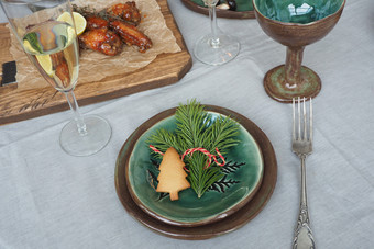 圣诞节表格设置棕绿色古董盘子古董叉云杉分支和姜饼树炸肉木托盘灰色的桌布和星星从橙色皮