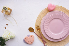 表格设置柳条餐巾两个粉红色的盘子饼干心金礼物盒子三个白色玫瑰味蕾勺子和叉白色表格复制空间平布局
