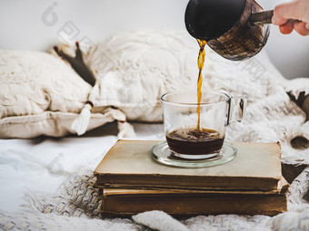 女手倒香咖啡杯的背景老书枕头和格子早餐的早期阳光明媚的早....女手倒香咖啡杯