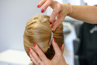 专业服务的美容沙龙年轻的女人与金发女郎头发有使发型为婚礼聚会，派对