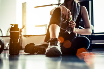 体育运动女人坐着和休息后锻炼锻炼健身健身房与蛋白质摇喝水地板上放松概念强度培训和身体构建主题温暖的和很酷的<strong>语气</strong>