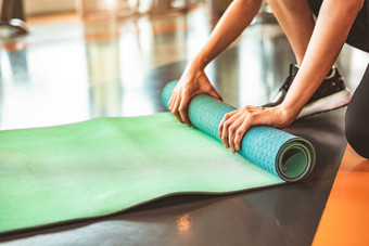 关闭运动女人折叠瑜伽床垫体育运动健身健身房培训中心背景锻炼席滚动保持后瑜伽类锻炼和体育运动培训概念手地毯
