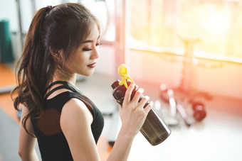 亚洲美丽的女人喝蛋白质摇喝水体育运动健身培训健身房体育和人概念健身和锻炼主题太阳耀斑效果