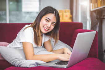 年轻的女人冲浪的互联网移动PC红色的沙发快乐的手势情绪情感销售和在线购物概念商人和市场营销幸福新业务交易员和企业家