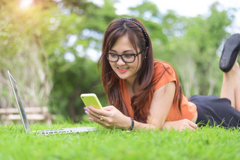 快乐亚洲女人使用智能手机当放松公园人和生活方式概念技术和放松<strong>主题</strong>在户外休闲和<strong>活动主题</strong>移动PC电脑元素