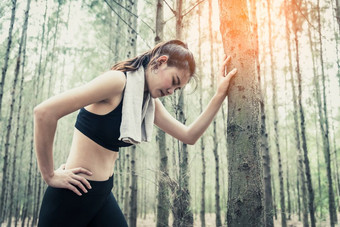 亚洲美女人累人的从慢跑森林精益树毛巾和汗水元素体育运动和健康的概念慢跑和运行概念放松和腰疼痛主题在户外活动主题