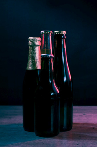 轮廓四个啤酒瓶黑色的背景与蓝色的和粉红色的灯那照亮他们从一个一边轮廓四个啤酒瓶黑色的背景与蓝色的和粉红色的灯那照亮他们从一个一边