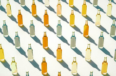 空中视图行玻璃瓶原型站白色背景各种各样的颜色苏打水瓶与长阴影对齐行复古的喝瓶概念