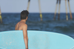冲浪者持有他的蓝色的冲浪板生活方式