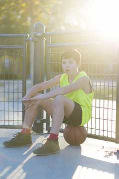 年轻的篮球球员坐着的法院穿黄色的无袖
