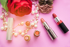 装饰平躺作文与色彩斑斓的口红珍珠和花前视图粉红色的背景