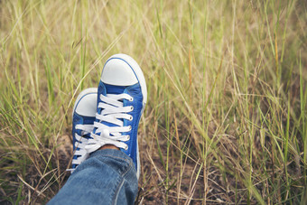 蓝色的<strong>运动鞋</strong>漂亮的女人穿牛仔裤和蓝色的<strong>运动鞋</strong>绿色草地