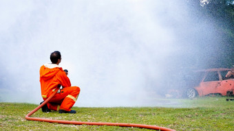 消防队员战斗与火焰使用火软管化学水泡沫喷雾引擎消防队员穿硬他身体安全西装统一的为保护救援培训火战斗灭火器
