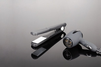 灰色席电手持头发铁和灰色干燥机为头发沙龙理发师商店的灰色镜子背景灰色头发铁和灰色干燥机的灰色镜子背景