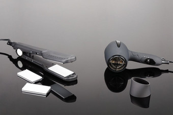 灰色席电手持头发铁和灰色干燥机为头发沙龙理发师商店的灰色镜子背景灰色头发铁和灰色干燥机的灰色镜子背景
