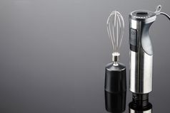 黑色的塑料电手搅拌机与不锈钢钢身体和附件的灰色镜子背景复制空间搅拌机与附件的灰色镜子背景