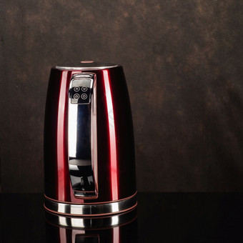画红色的颜色不锈钢钢无线电水壶与棕色（的）塑料处理的黑色的镜子背景与复制空间红色的不锈钢钢水壶的黑色的镜子背景