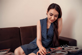 年轻的亚洲女孩条纹衣服坐在的沙发上和把卷磁<strong>磁带</strong>古董<strong>磁带录音机</strong>