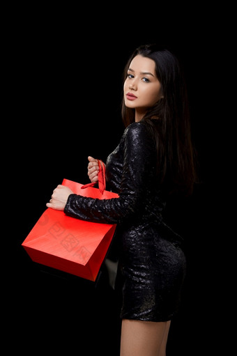 年轻的女人黑色的衣服快乐与礼物购物黑色的和红色的袋黑色的孤立的背景年轻的女人黑色的衣服快乐与礼物购物黑色的和红色的袋黑色的孤立的背景