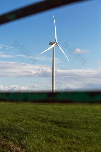 风车与新鲜的绿色草和清晰的蓝色的天空夏天能源概念附近栅栏风车与新鲜的绿色草和清晰的蓝色的天空夏天能源概念附近栅栏