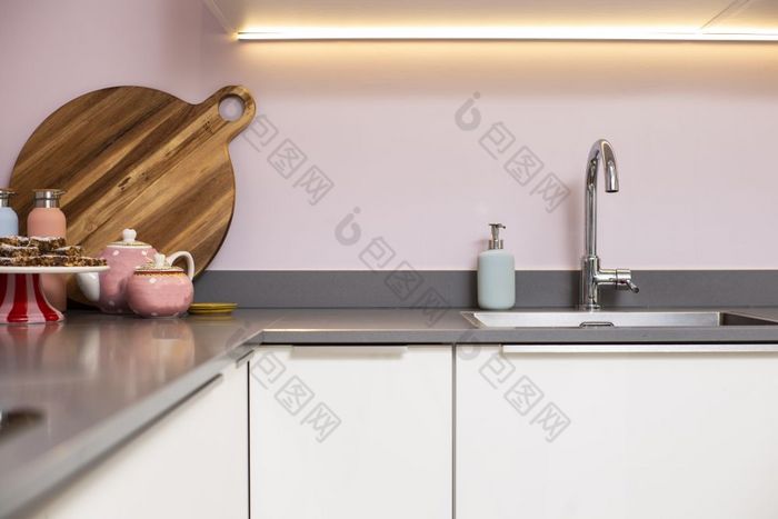 特写镜头计数器和现代厨房钢水槽与粉红色的墙和装饰现代光室内清洁特写镜头计数器和现代厨房钢水槽与粉红色的墙和装饰现代光室内